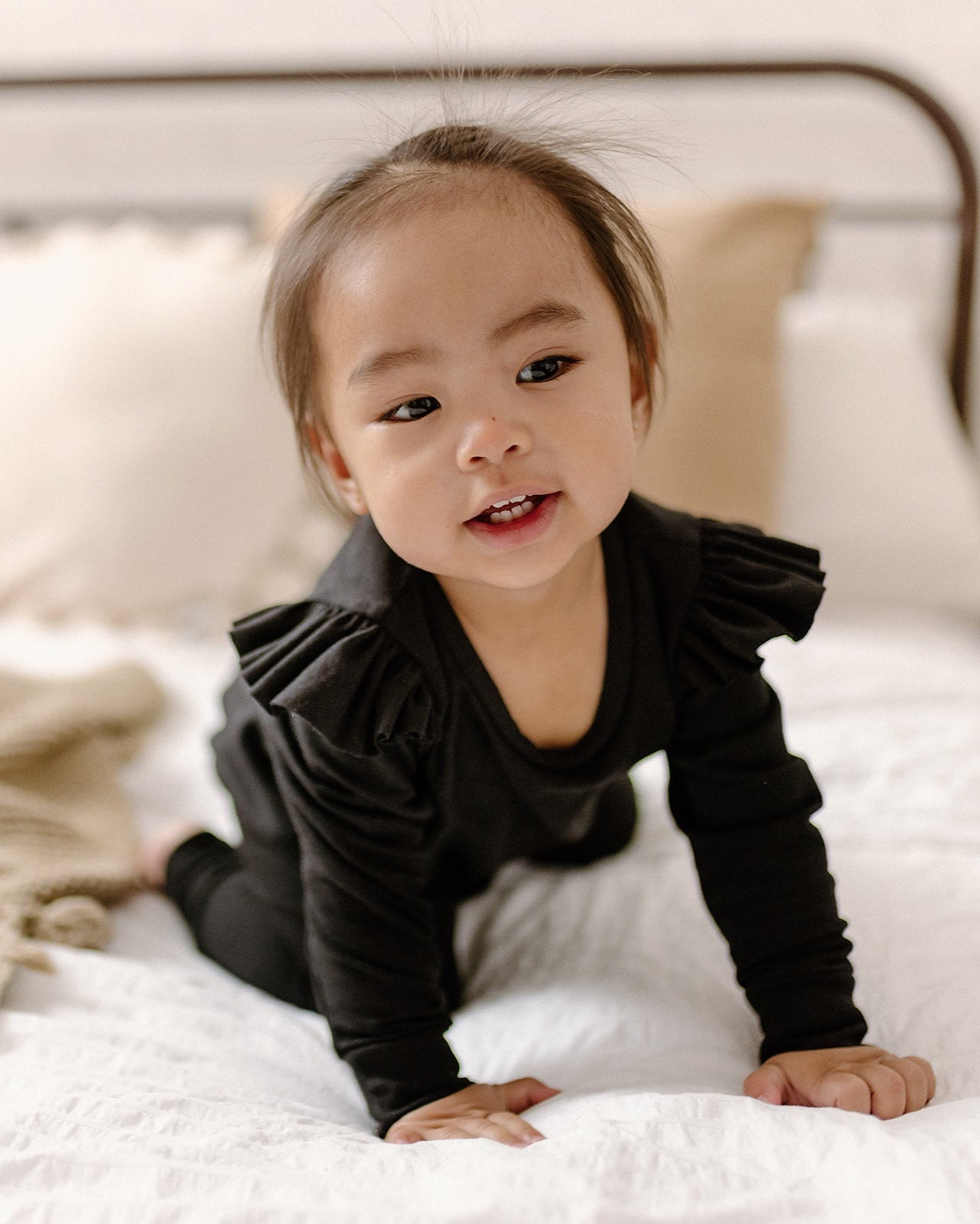 Little girl in a burgundy ruffle romper and black toque