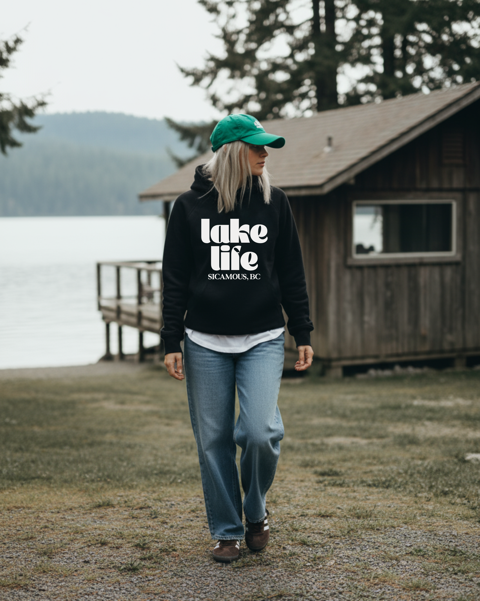 Four women walking and laughing together in lake life hoodies, with the blonde woman wearing a navy cap