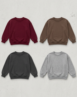 All four lounge sweaters in burgundy, brown, charcoal and heather grey on a concrete flat lay, with extra space for a 4:5 crop
