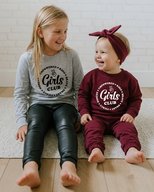 Both girls sitting together and laughing with the toddler’s sweater visible