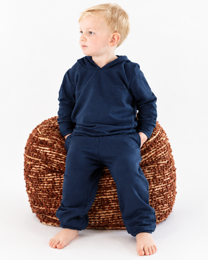Boy in a navy hoodie and sweatpants with extra background space for cropping
