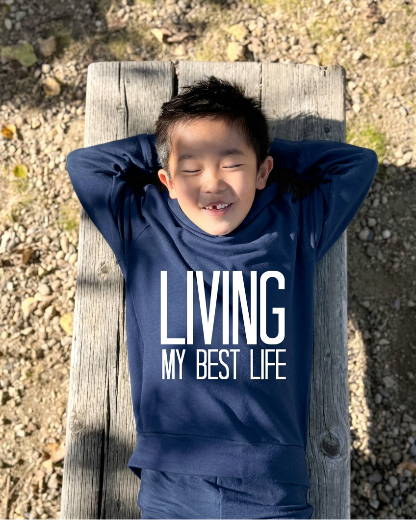 Boy sitting on the bench in matching navy sweats and brown Blundstone boots