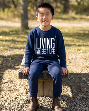Boy sitting on the bench in matching navy sweats and brown Blundstone boots