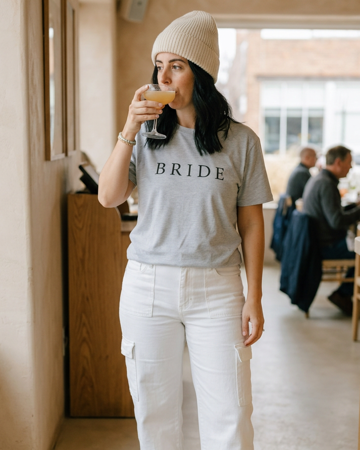 Bride tee styled with a cream beanie, white cargos and brown Sambas in a restaurant