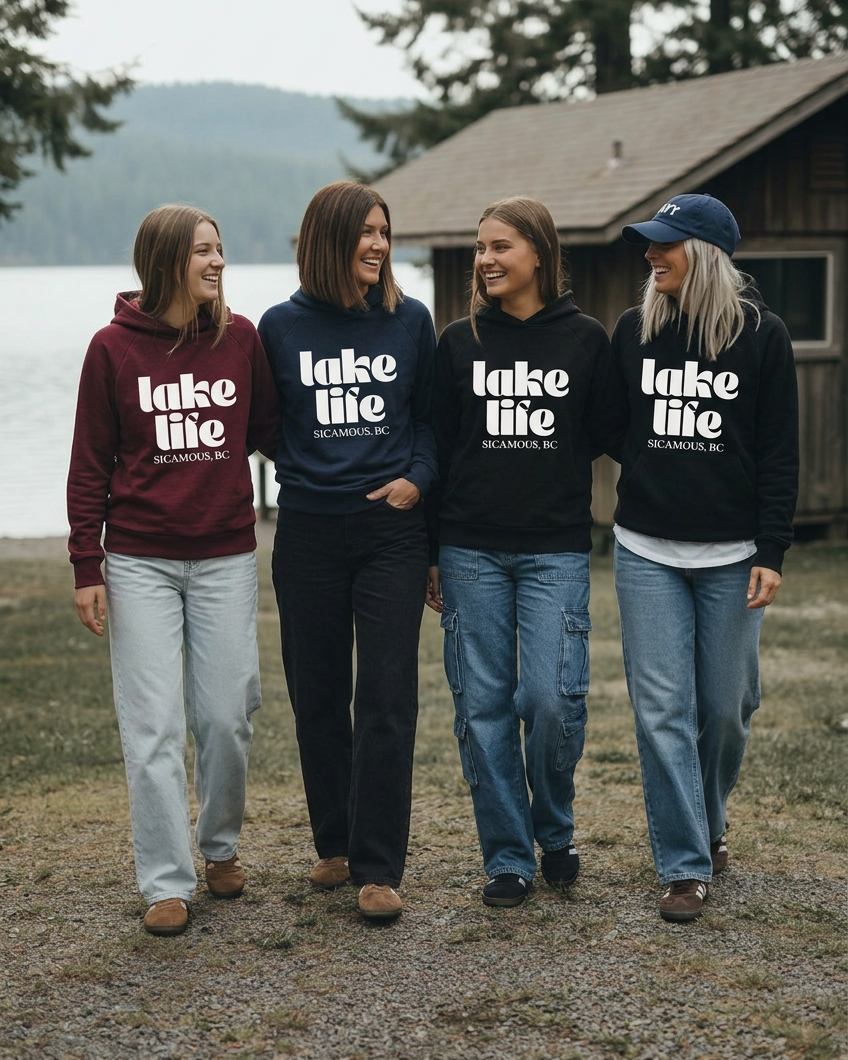 Four women walking and laughing together in lake life hoodies, with the blonde woman wearing a navy cap