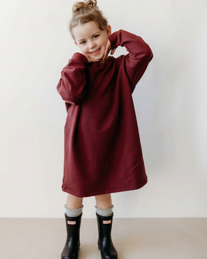 Full-body view of the girl in her burgundy dress with black Hunter-style boots and ruffled grey socks