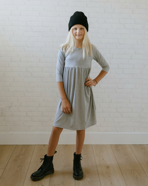Girl in her grey dress styled with black lace-up combat boots and a black knit beanie