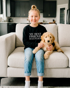 Girl sitting on the couch smiling at her goldendoodle
