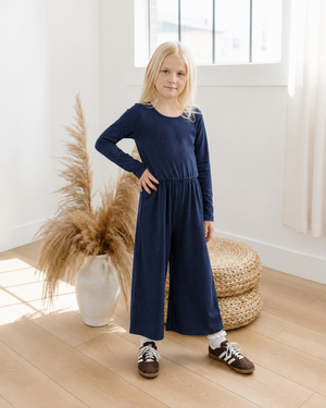 Girl wearing a navy wide-leg romper in a bright studio