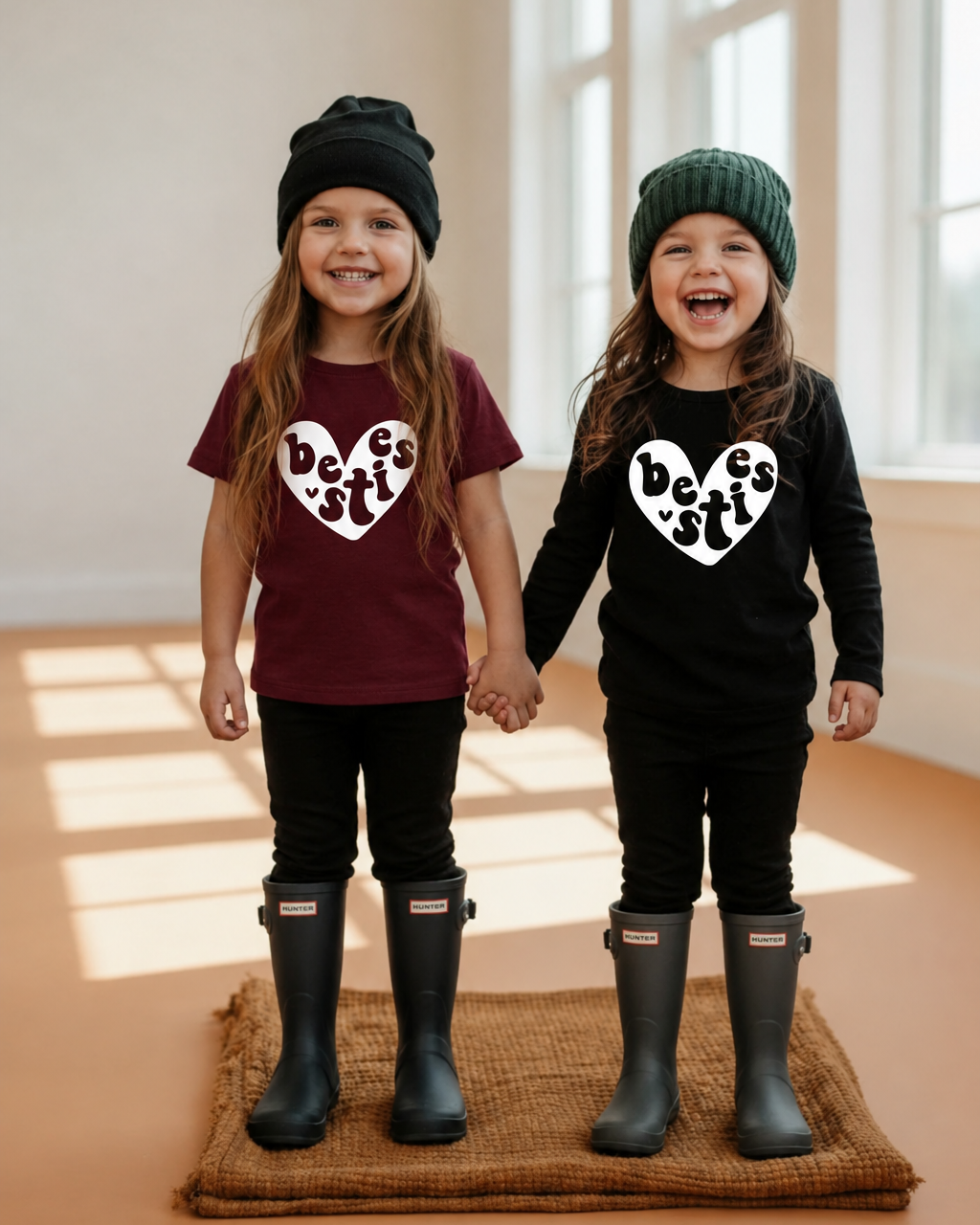 Girls holding hands with matching white Besties hearts on burgundy and black shirts