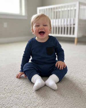 Little boy in a navy romper with a black chest pocket
