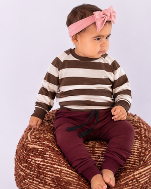 Little girl in burgundy bottoms and a brown-and-cream striped top