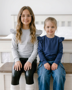 Older girls seated on the bench in Cynthia crewnecks, cropped above their feet