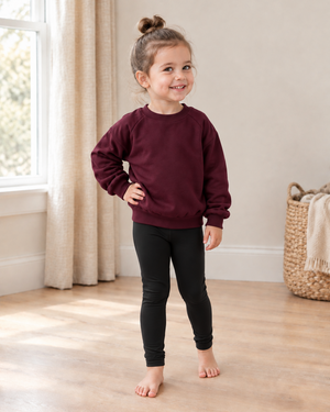 Same girl in a burgundy slouchy sweater and black leggings in a new pose