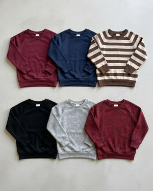 Six crewnecks in two rows: burgundy, navy, brown stripe, black, heather grey, and burgundy bows, with space for a 4:5 crop