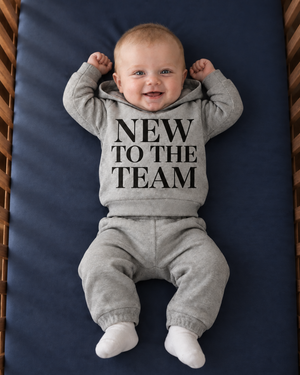 Softly lit baby in a walnut crib with dimensional navy cotton bedding