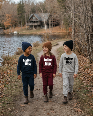 Three kids walking and laughing along the lakeside path
