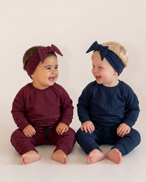 Two babies with pointed-end burgundy and navy topknots